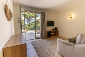 a living room with a couch and a television at Hôtel L'Escalet in Ramatuelle