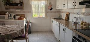 a kitchen with white cabinets and a table and a sink at Casa Rural Villa Arcadia in Corvera