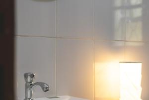 a bathroom mirror with a sink and a lamp at JOSIRE Residence in Entebbe