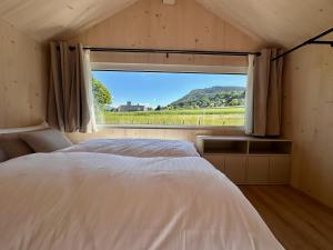 a bedroom with a bed and a large window at Die Tinys - Ferienhäuser am Attersee in Nussdorf am Attersee