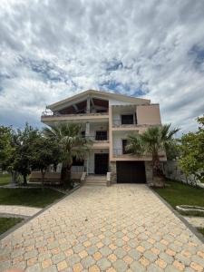 a large white building with palm trees in front of it at Villa Velipoj in Velipojë