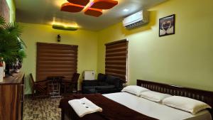 a bedroom with a bed and a chair and a ceiling fan at SPATHODEA in Vagamon