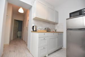 a white kitchen with white cabinets and a refrigerator at ApartHostel "Przy Rynku" Wrocław in Wrocław