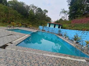 a swimming pool with blue water in front of a house at Nalari Resort in Borpāni