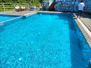 a man standing next to a blue swimming pool at Nalari Resort in Borpāni