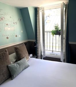 a bedroom with a large bed with a window at Hôtel des 3 Poussins in Paris
