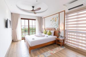 a bedroom with a bed and a ceiling fan at Lúa Boutique Hoi An Hotel in Tân Thành (1)