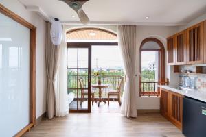 a kitchen with a view of a table and a balcony at Lúa Boutique Hoi An Hotel in Tân Thành (1)