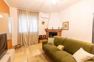 a living room with a green couch and a fireplace at Sweet Nonna Dora Corato - Casa con Parcheggio in Corato