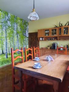 a wooden dining room table with chairs and a kitchen at Gościna U kowala in Lachowice