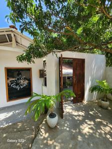 a house with two potted plants in front of a door at Early birds in Arugam Bay