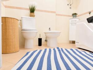 a bathroom with a toilet and a blue and white striped rug at SPLENDID Sunset Penthouse in Rafailovici +35 photos