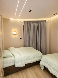 a bedroom with two beds and a window at Cyra gate Suncapital compound شقة في كامبواند صنكابيتال بوابة كايرا بالقرب in ‘Ezbet `Abd el-Ḥamîd