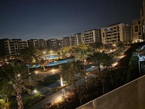 a resort at night with palm trees and lights at Cyra gate Suncapital compound شقة في كامبواند صنكابيتال بوابة كايرا بالقرب in ‘Ezbet `Abd el-Ḥamîd +4 photos