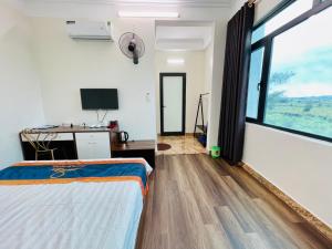 a bedroom with a bed and a desk and a tv at Khách sạn Cao Sơn in Cửa Ông