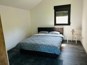 a bedroom with a bed with a blue comforter and a window at Lux apartmani in Bihać