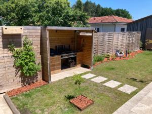 a backyard with a barbecue grill in a fence at Chai Nous - votre villa au cœur des Landes - classée 4 étoiles in Rion-des-Landes