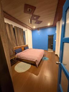 a bedroom with a bed and a blue wall at Tree house munsyari in Munsyari +38 photos