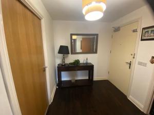 a hallway with a table and a lamp and a mirror at Colindale Central Apartment in Colindale