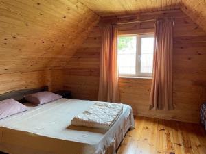 a bed in a wooden room with a window at Затишок in Svityazʼ