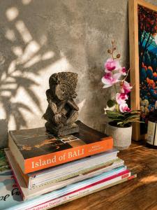 a stack of books on a table with a statue on top at LUV-Balian in Balian