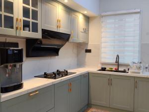 a kitchen with white cabinets and a sink and a microwave at 25 Homestay Pulai in Johor Bahru