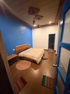 a bedroom with a bed and a blue wall at Tree house munsyari in Munsyari