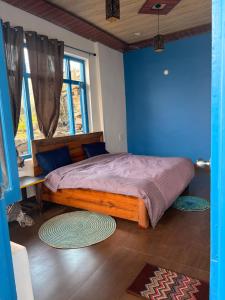 a bedroom with a large bed with a blue wall at Tree house munsyari in Munsyari