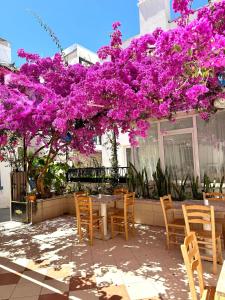 a table and chairs under a tree with purple flowers at Kale Otel Bodrum in Bodrum City
