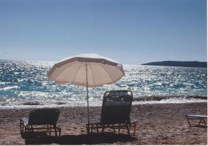 two chairs and an umbrella on the beach at Trifilli in Lourdata