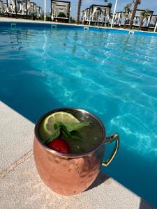 a cup with a strawberry in it next to a swimming pool at KIBO Boutique in Frumuşani