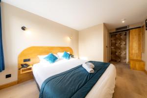 a bedroom with a large bed with blue pillows at Logis Hôtel & Restaurant Cap Hôtel in Noyelles-Godault +66 photos