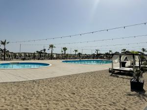 a resort with two swimming pools and palm trees at KIBO Boutique in Frumuşani