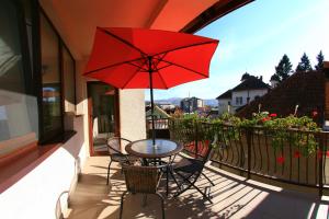 a table and chairs with a red umbrella on a balcony at Pensiunea Maria in Călimăneşti