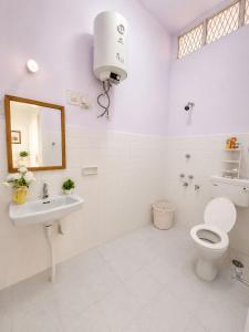 a white bathroom with a toilet and a sink at Clean Culture Retreat in Mysore +3 photos