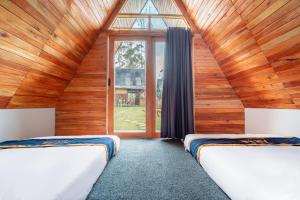 two beds in a room with a large window at The Cabin Artana By ARBA in Palayangan