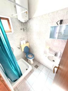 a bathroom with a blue shower curtain and a toilet and sink at Apartmani Leona in Metajna +37 photos