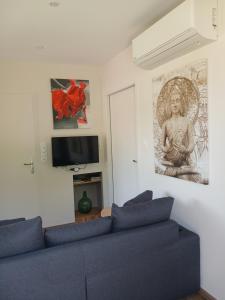 a living room with a blue couch and a painting on the wall at L'Ardétente - Le cosy, Piscine et SPA en Ardèche, Adults only in Lussas