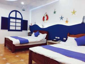 una camera con due letti e una parete blu e bianca di Zi Jìng Fang Inn a Città Vecchia di Hengchun