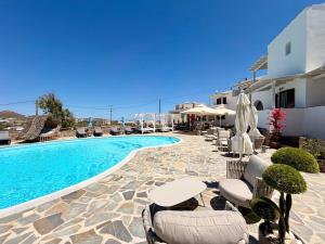 a swimming pool with tables and chairs next to a building at Naxos Mare in Agia Anna Naxos