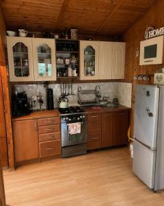 a kitchen with wooden cabinets and a white refrigerator at Merylula - Domek nad jeziorem in Przydwórz