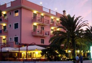 un grand bâtiment rose avec des palmiers devant lui dans l'établissement Il Casale, à Martinsicuro