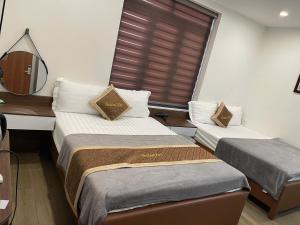 two beds in a small room with a window at Hotel Thái Lan in Hai Phong