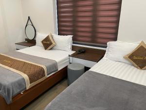 a bedroom with two beds and a window at Hotel Thái Lan in Hai Phong