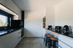 a kitchen with white cabinets and bar stools at Souto Village - Douro Verde - by FERO in Maureles