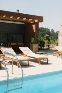 a pool with chaise lounges and chairs next to a building at Souto Village - Douro Verde - by FERO in Maureles