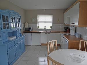 a kitchen with blue cabinets and a table in it at Ula Cottage in Saint Helens