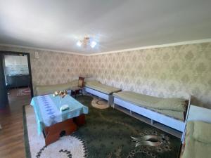 a living room with two beds and a table at ASAN ATA Guest House in Toktogul