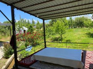 a porch with a bed and a field of flowers at ASAN ATA Guest House in Toktogul +2 photos