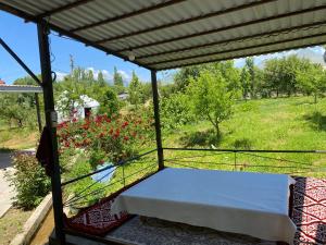 a porch with a bed and a field of flowers at ASAN ATA Guest House in Toktogul